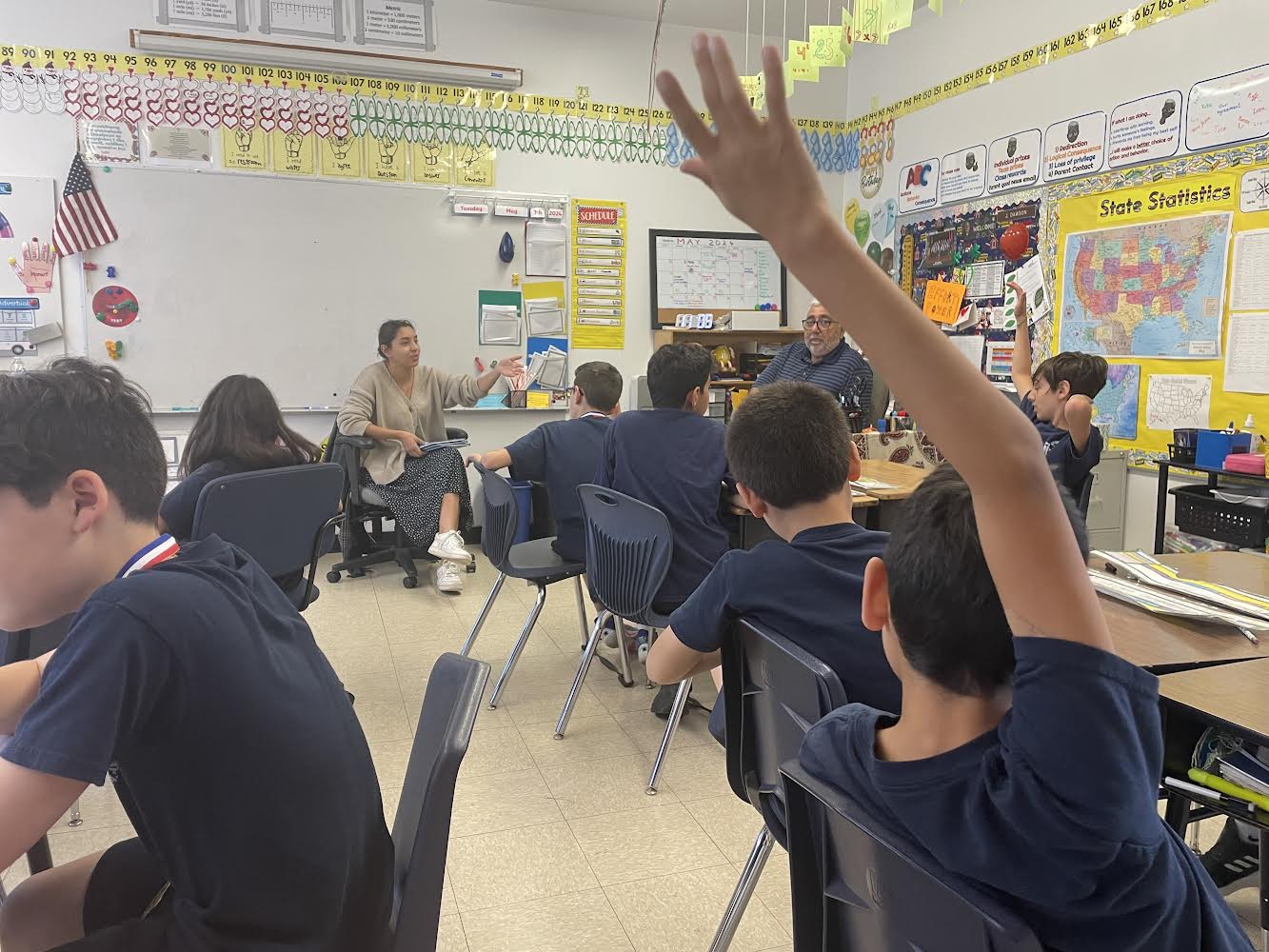 A student raising a hand in a classroom in Los Angeles